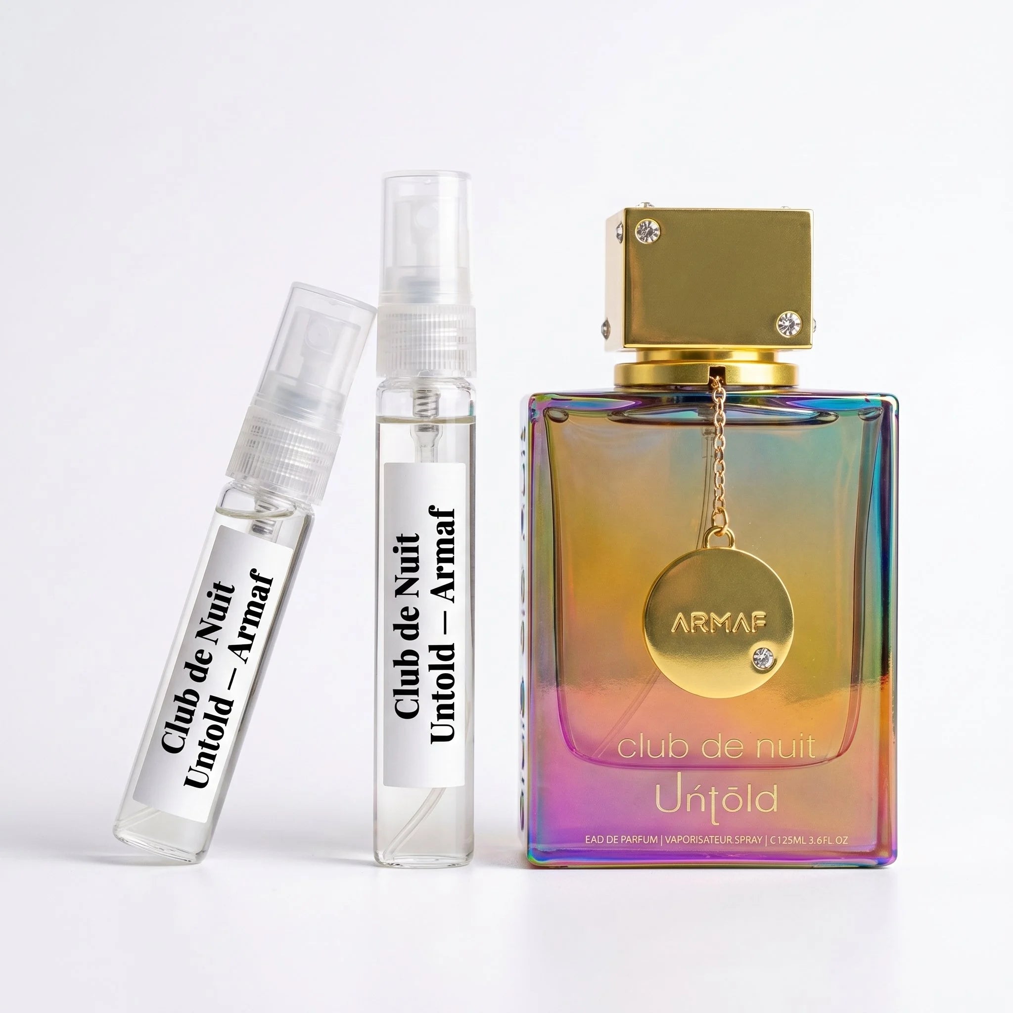Armaf Club de Nuit Untold decant vials with holographic iridescent bottle on white background luxury fragrance photography