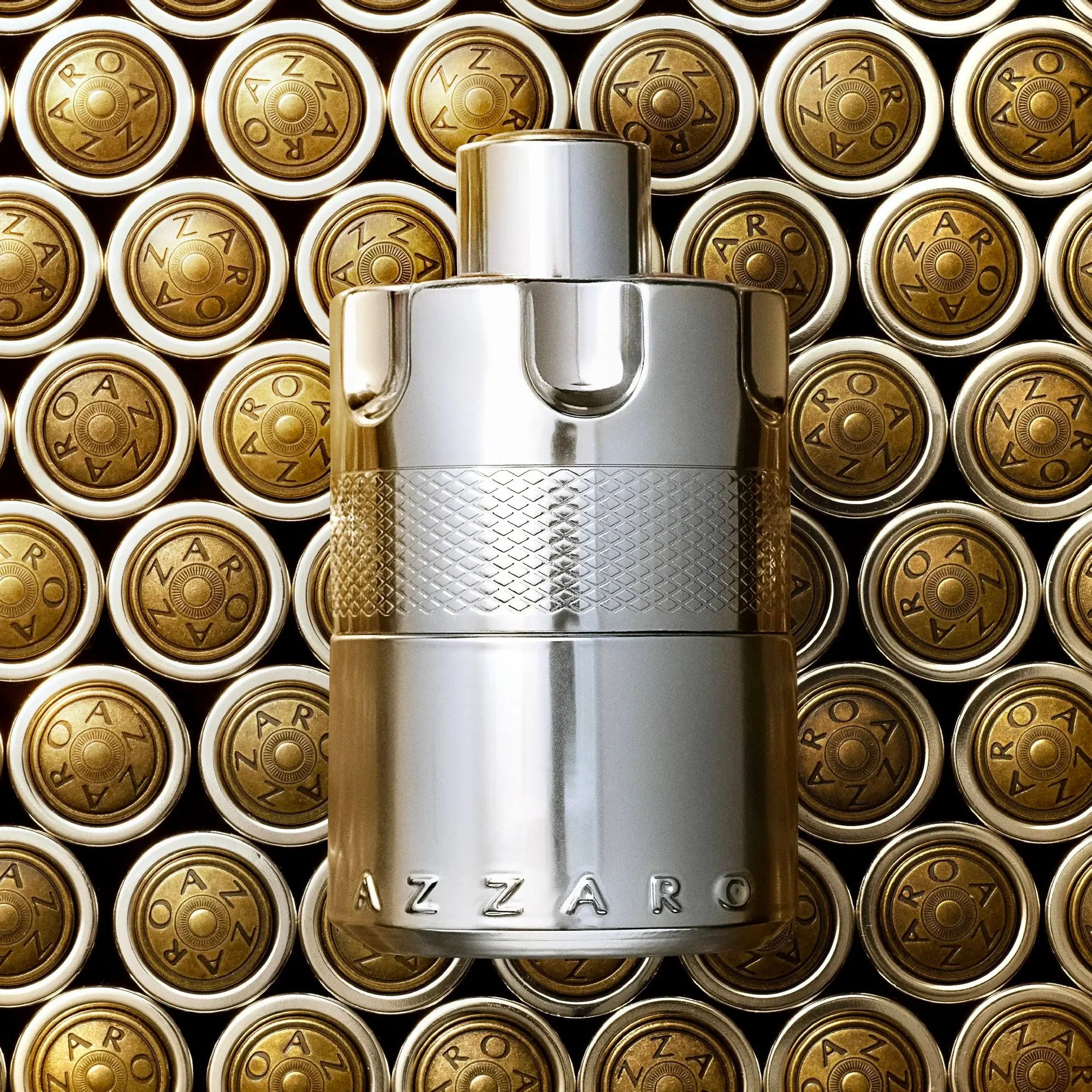 Silver Azzaro perfume bottle on a background of gold Azzaro packaging.