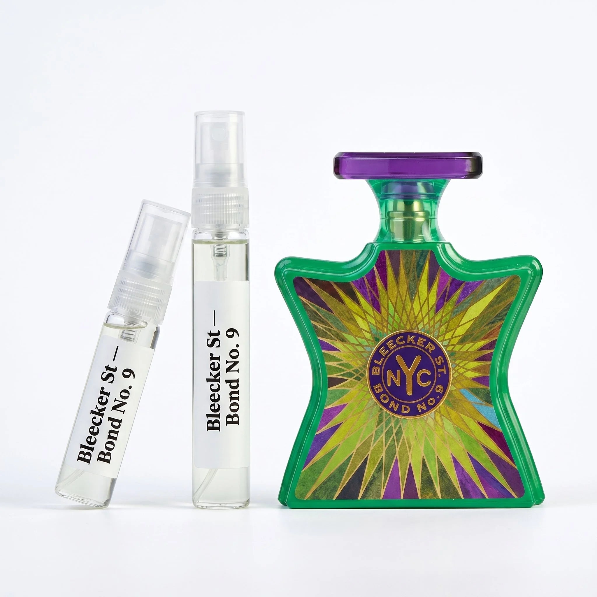 Bond No 9 Bleecker Street decant vials with vivid green purple starburst bottle on white background luxury fragrance photography