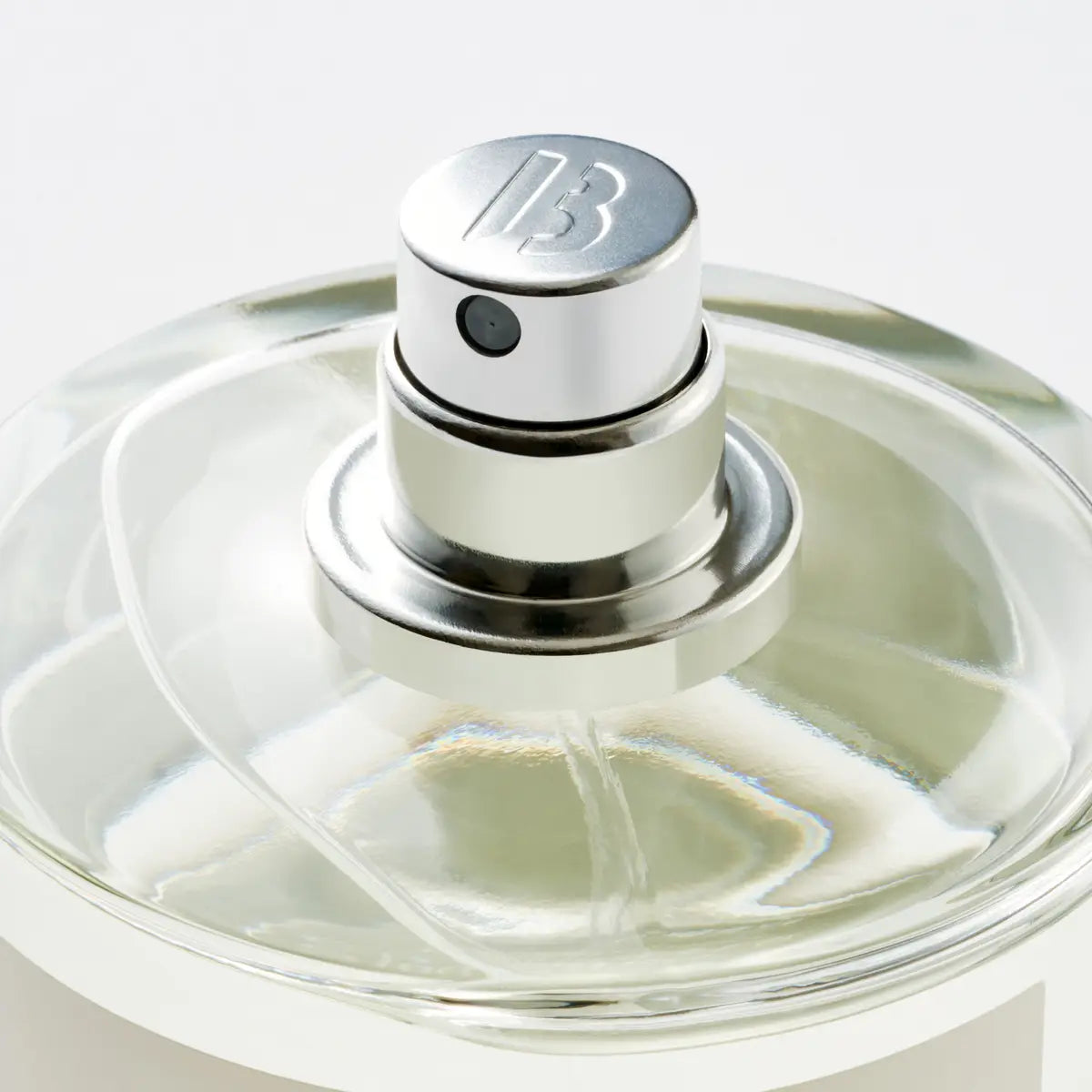 Close-up of a perfume bottle with a silver cap on a white background