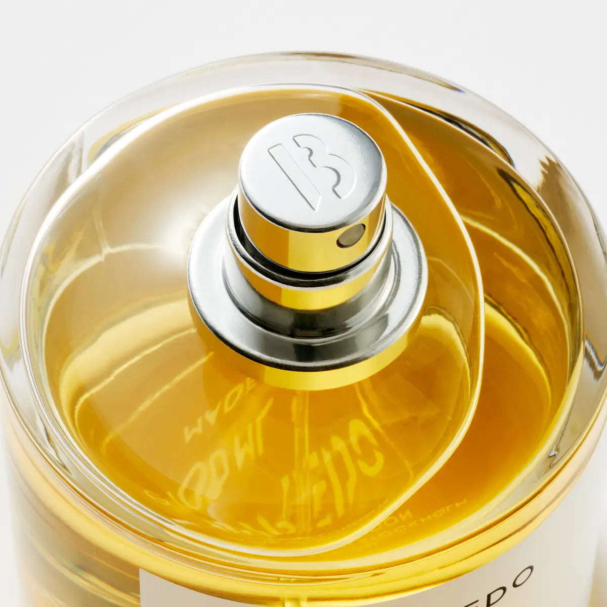 Close-up of a perfume bottle with a gold cap and clear body.