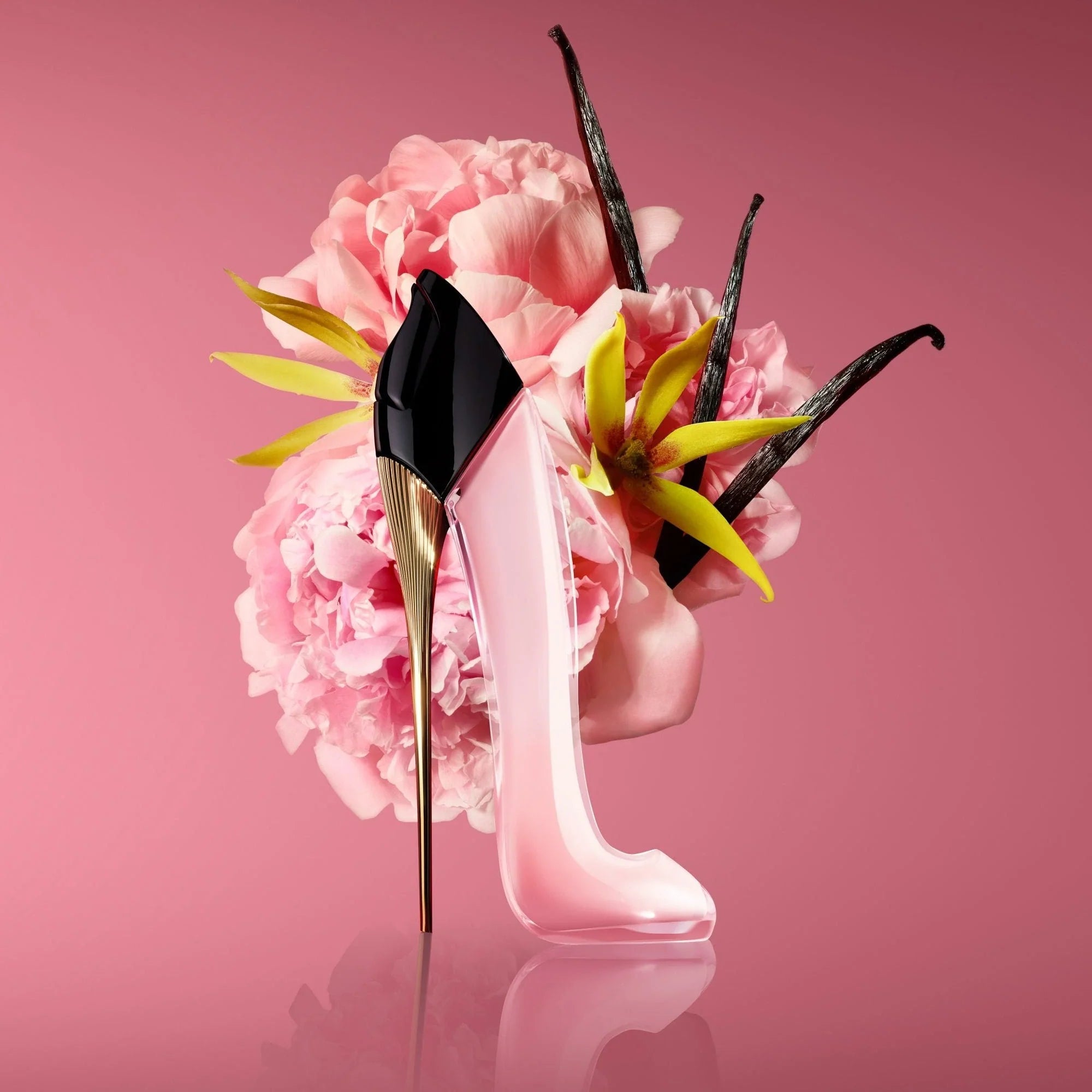 Pink high heel shoe with vanilla beans and flowers on a pink background