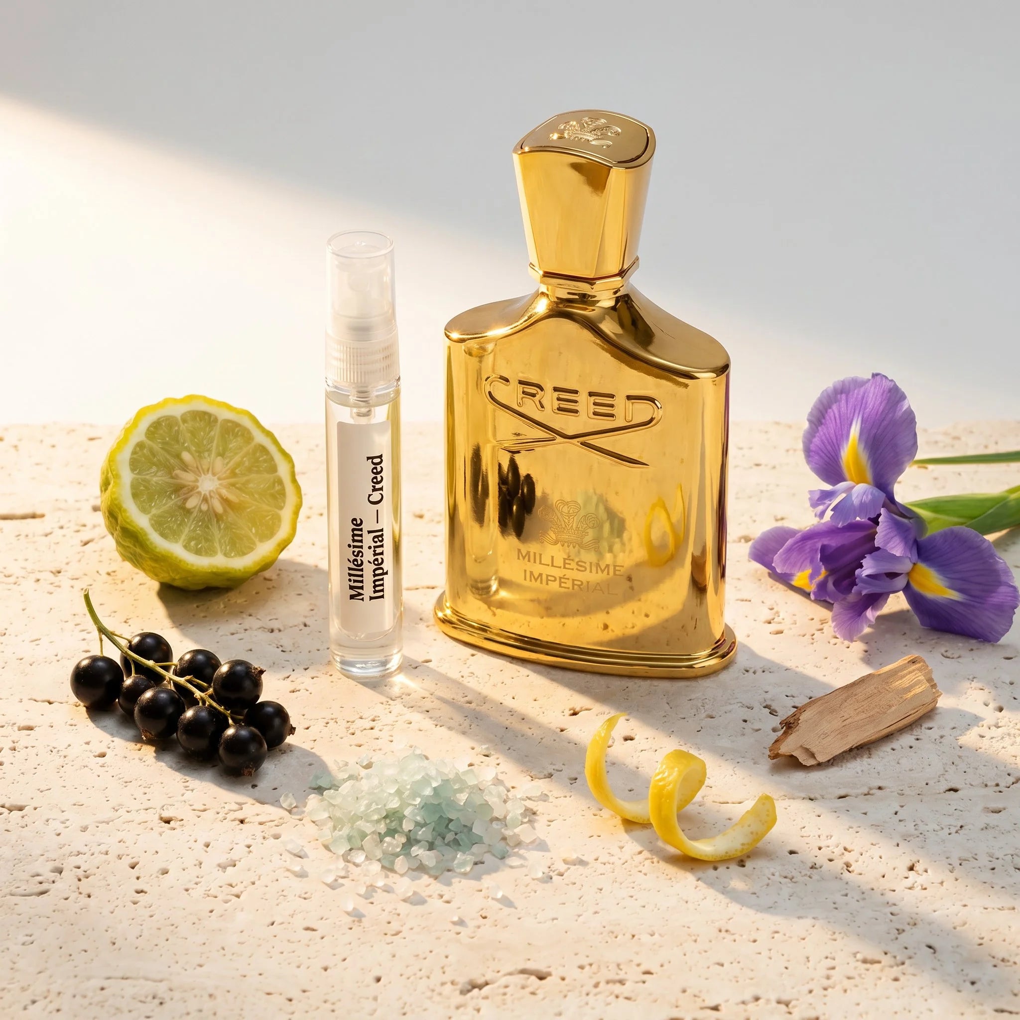 Creed Millesime Imperial bottle and decant on pale stone with bergamot blackcurrant sea salt iris and cedarwood fragrance notes flatlay