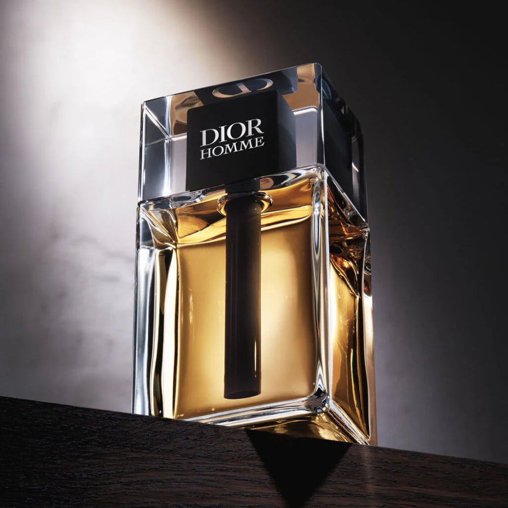 Dior Homme perfume bottle on a dark surface with a gradient background