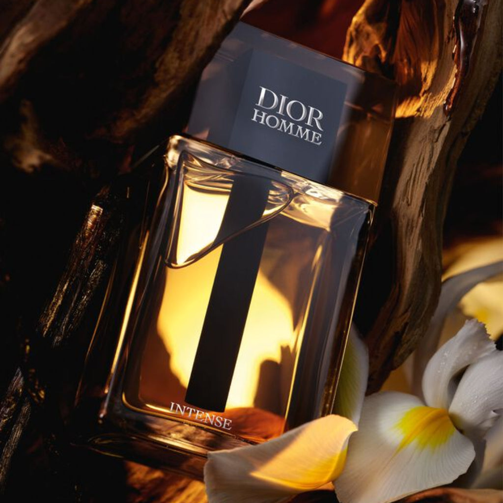 Dior Homme Intense perfume bottle with flowers and wood in the background