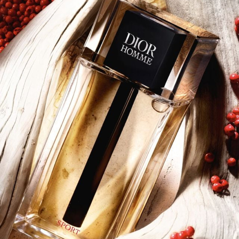 Dior Homme perfume bottle with berries on a textured surface