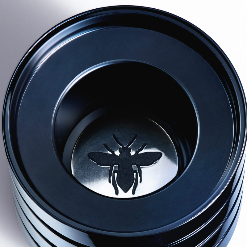 Stack of black plastic containers with a bee logo on a white background