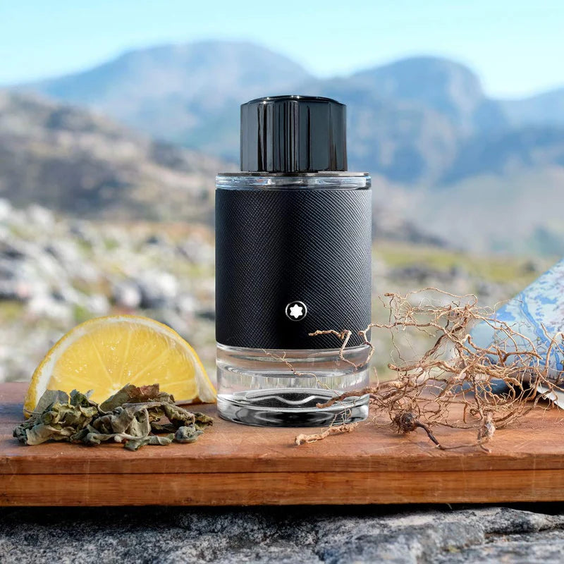 Black perfume bottle on a wooden surface with natural elements and mountains in the background