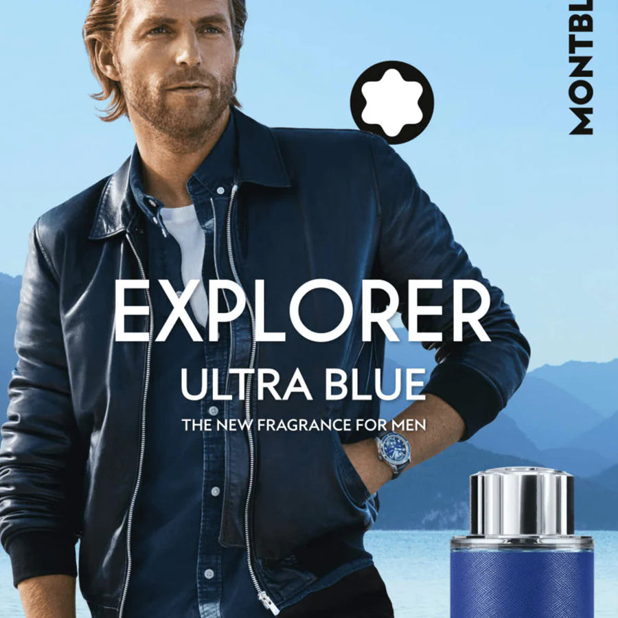 Man wearing a blue jacket with 'Explorer Ultra Blue' fragrance packaging in the foreground, set against a mountainous landscape.