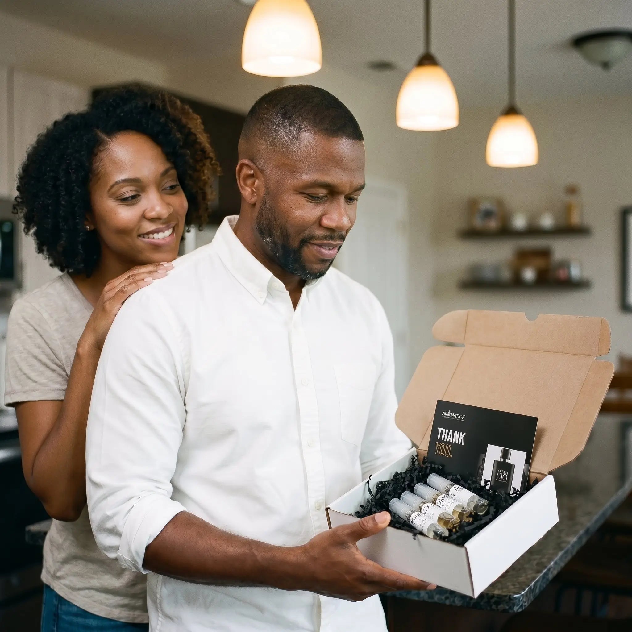 Couple Father's Day unboxing — man opening Aromatick fragrance bundle with wife in kitche