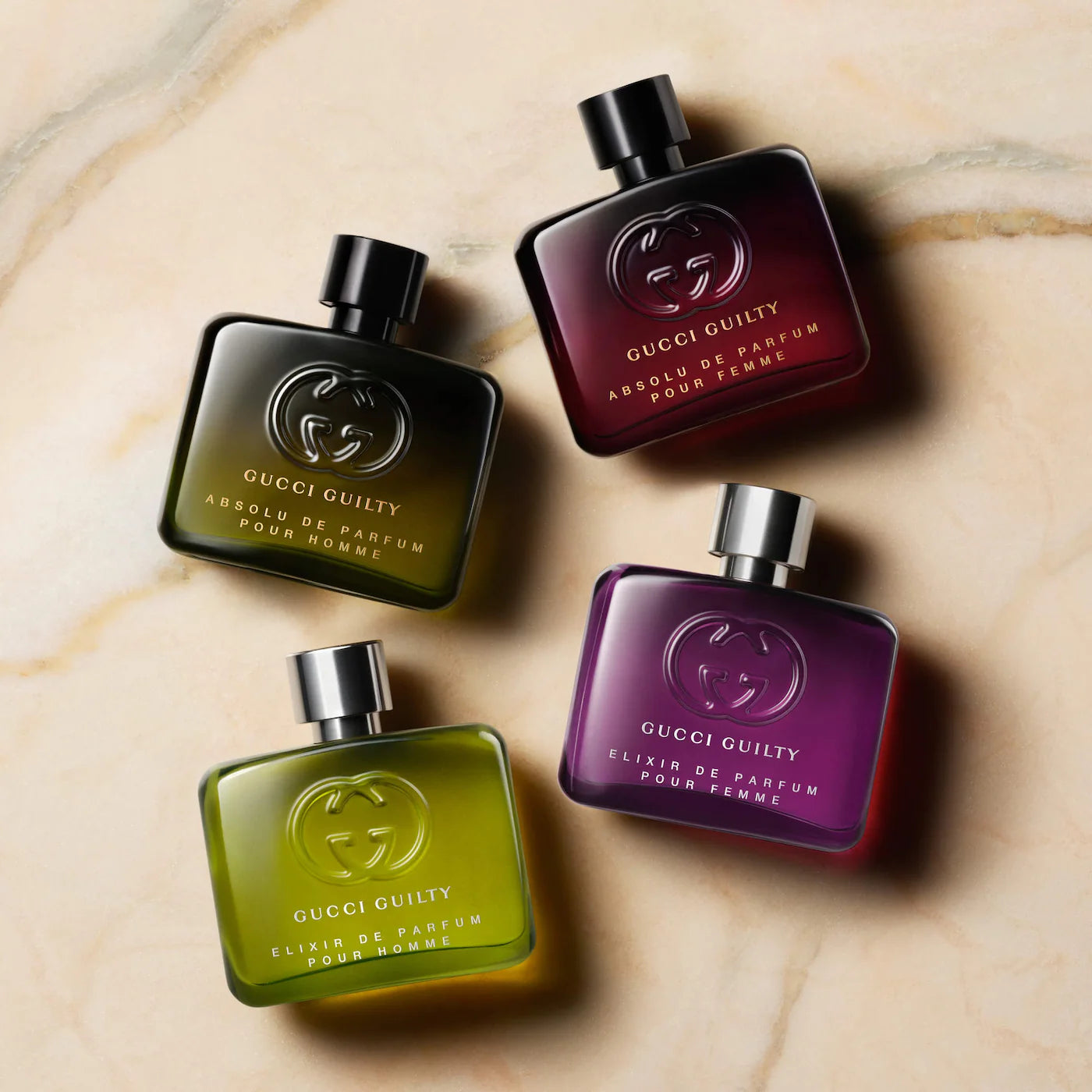 Four Gucci Guilty perfume bottles on a marble surface