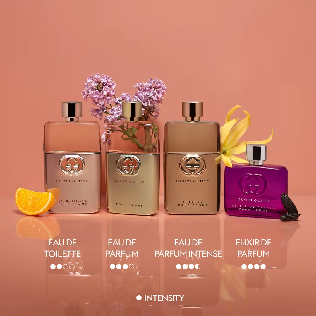 Four Gucci perfume bottles with flowers and an orange slice on a peach background