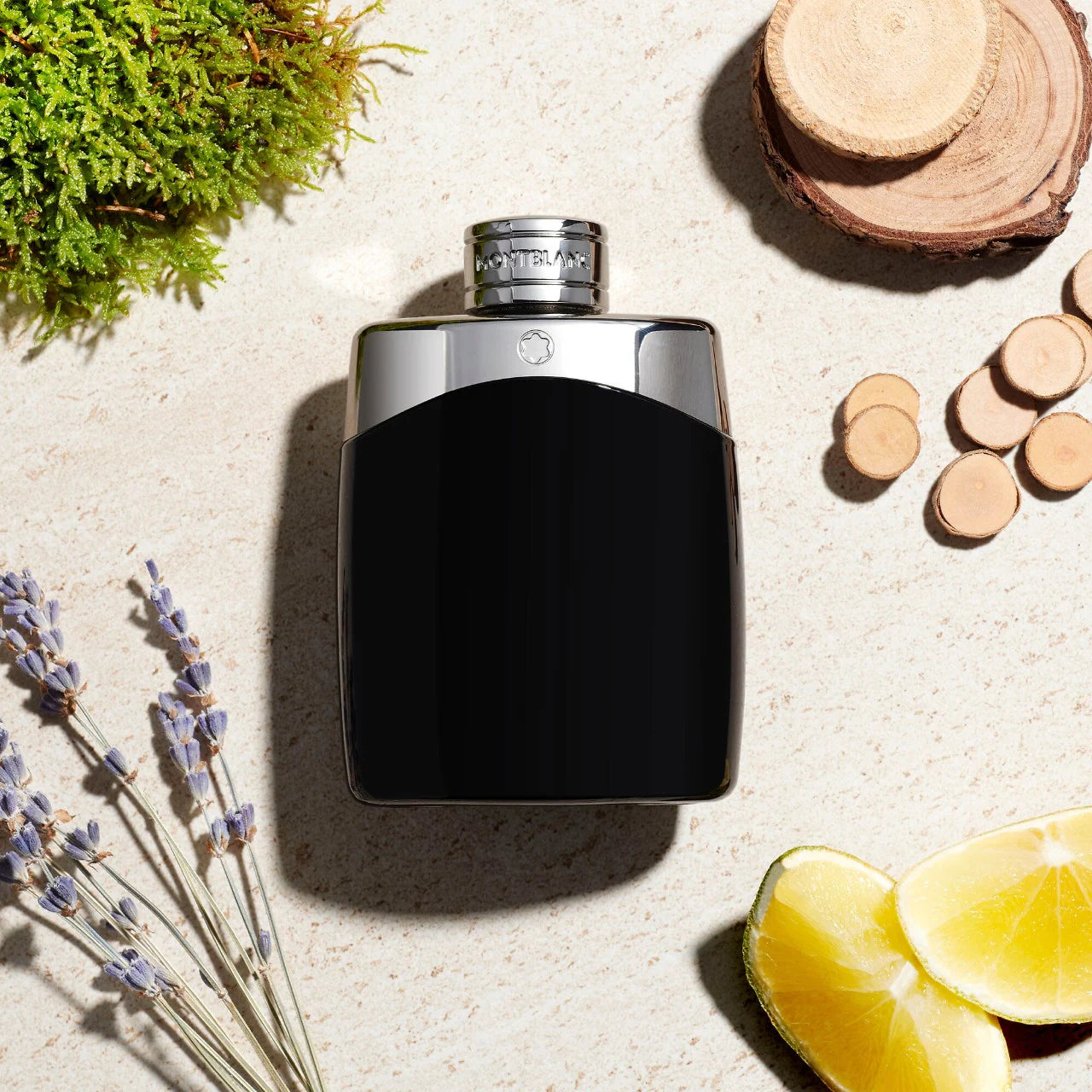 Black and silver perfume bottle on a textured surface with natural elements like lavender and lemon.