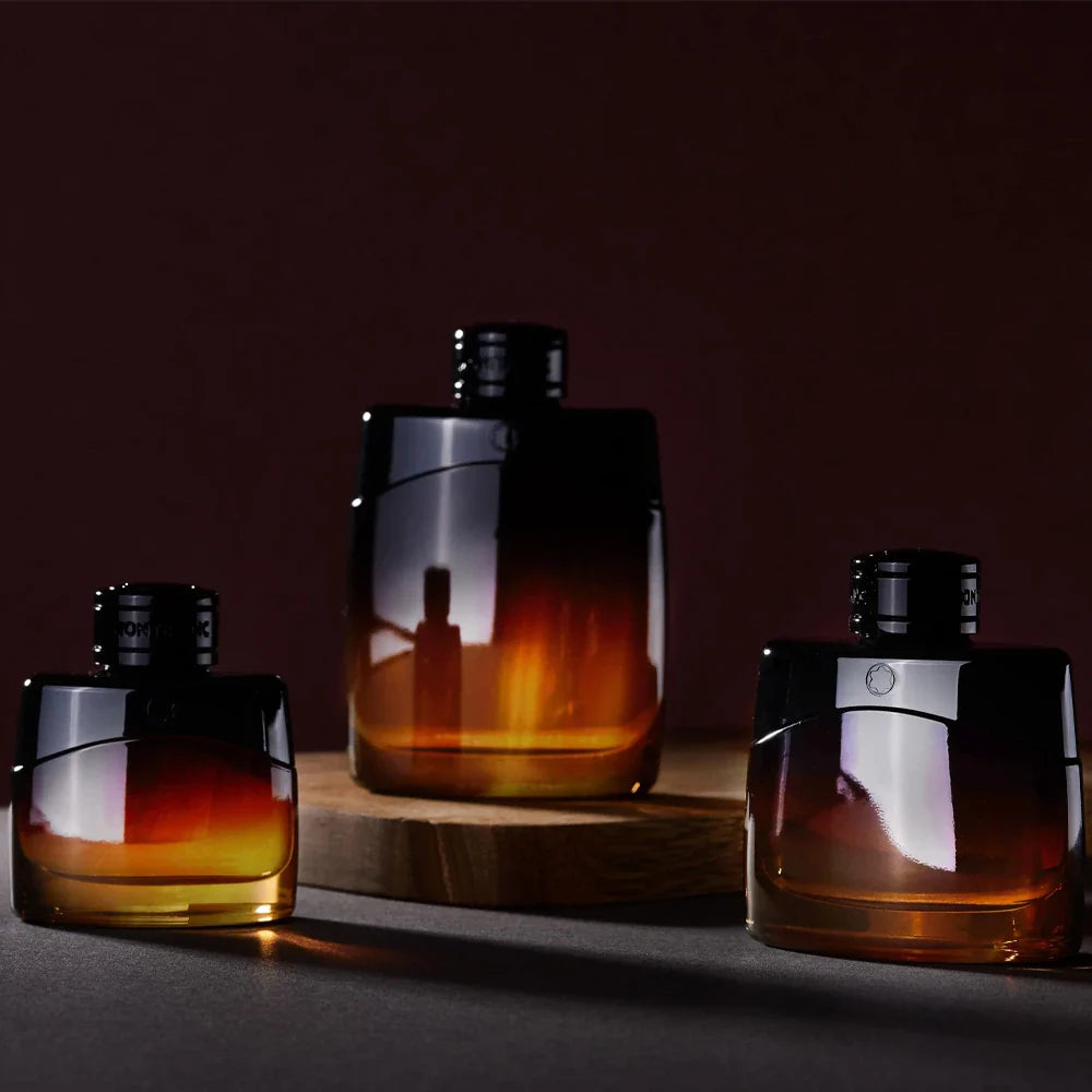 Three amber-colored perfume bottles with dark caps on a wooden surface against a dark background