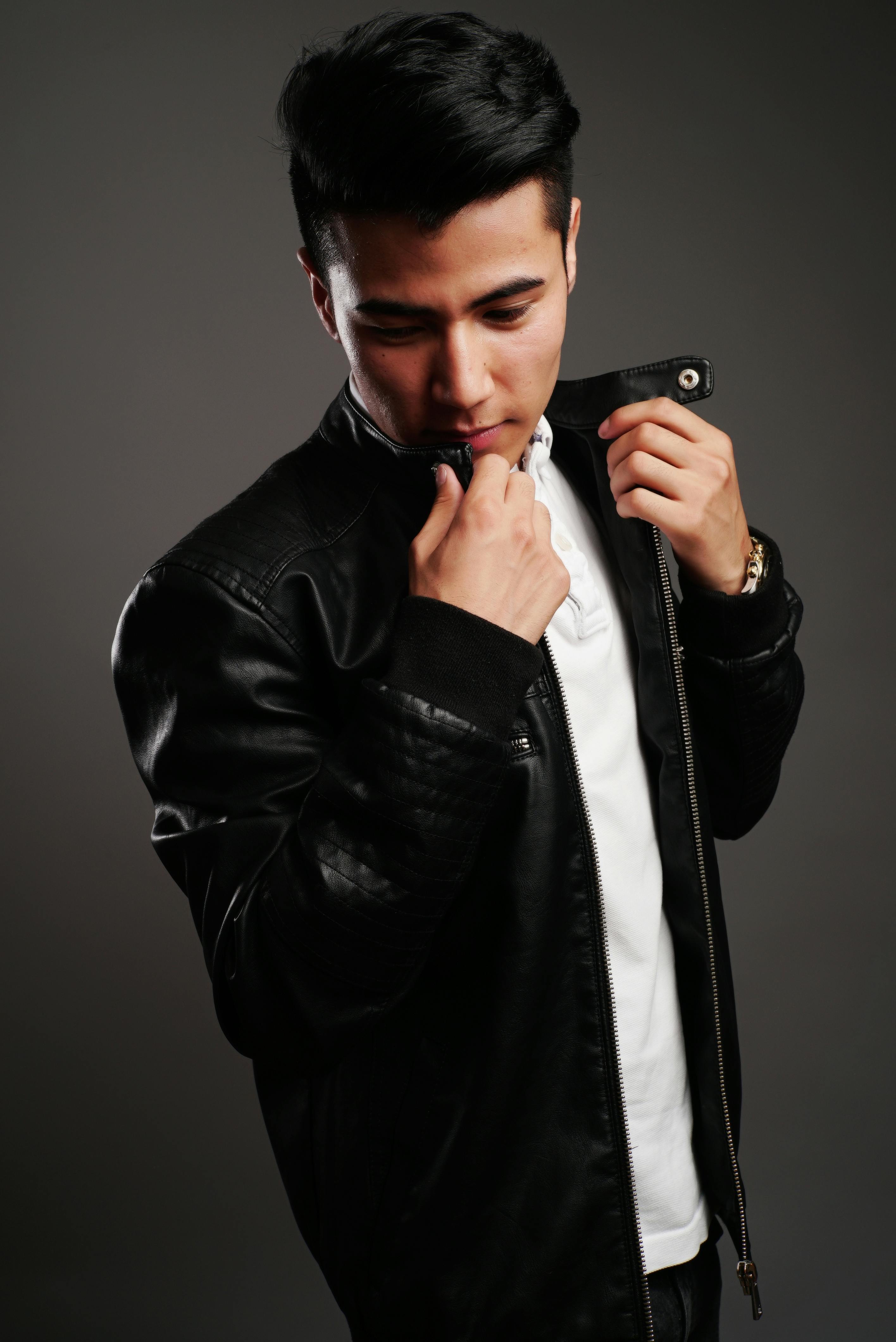 A man in a leather jacket next to a bottle of Afnan 9PM Rebel Extrait