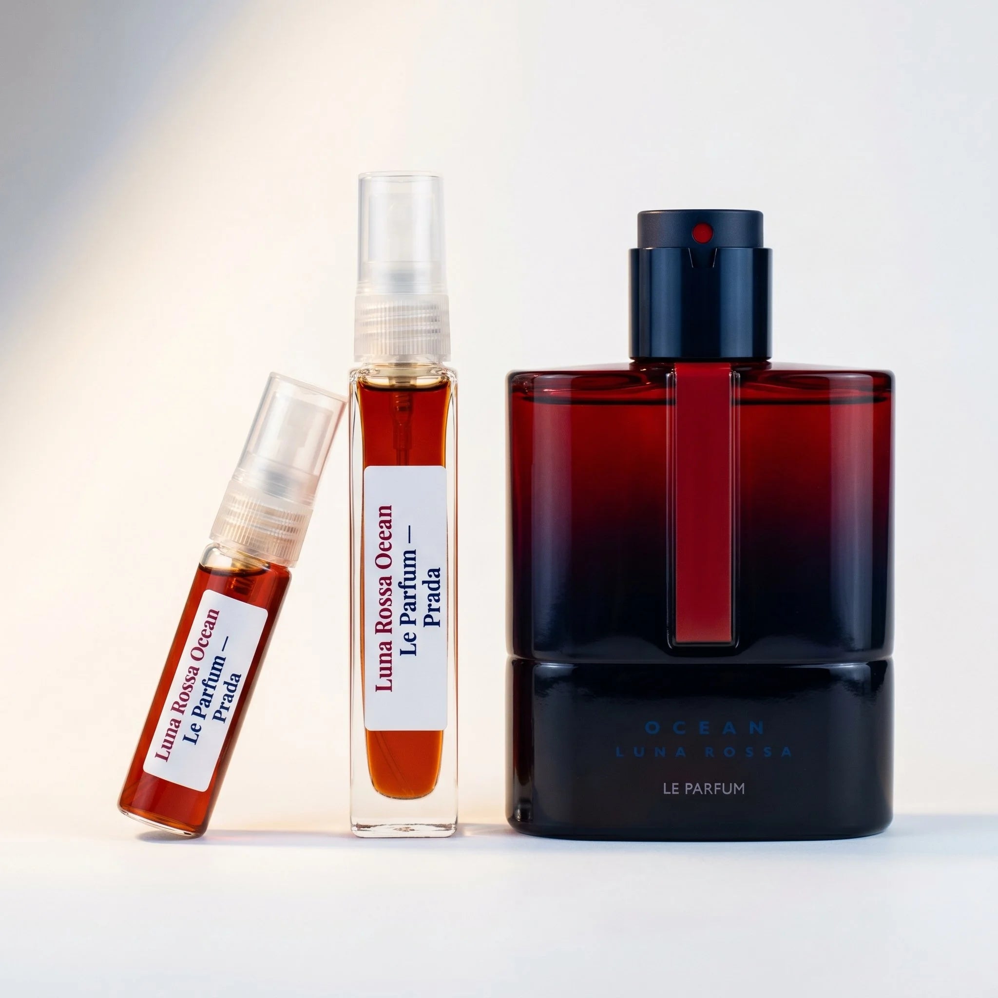 Prada Luna Rossa Ocean Le Parfum decant vials with crimson navy bottle on white background luxury fragrance photography