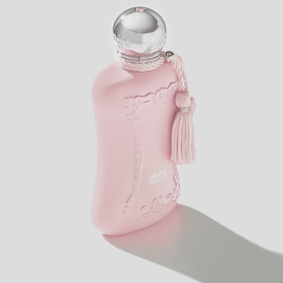 Angled view of PDM Delina Exclusif EDP pink perfume bottle casting a shadow, highlighting its feminine design and floral oriental scent.
