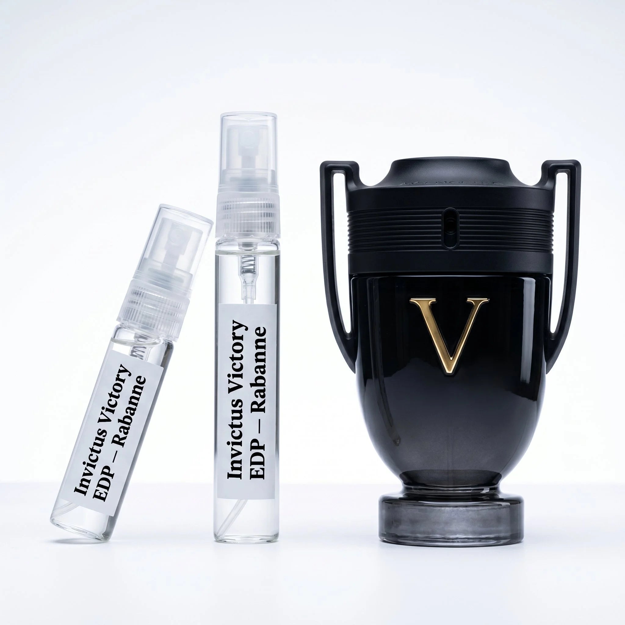 Rabanne Invictus Victory EDP decant vials with matte black trophy bottle gold V emblem on white background luxury fragrance photography
