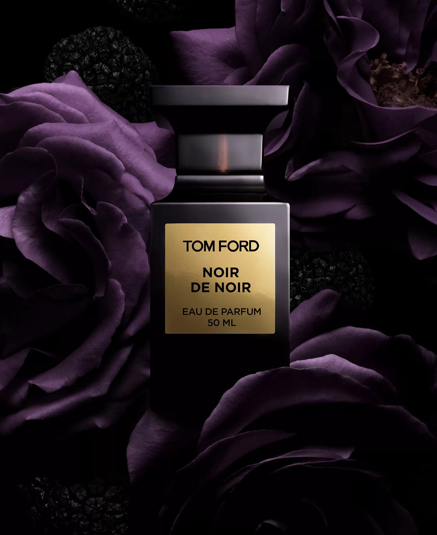 Tom Ford Noir de Noir perfume bottle surrounded by purple flowers