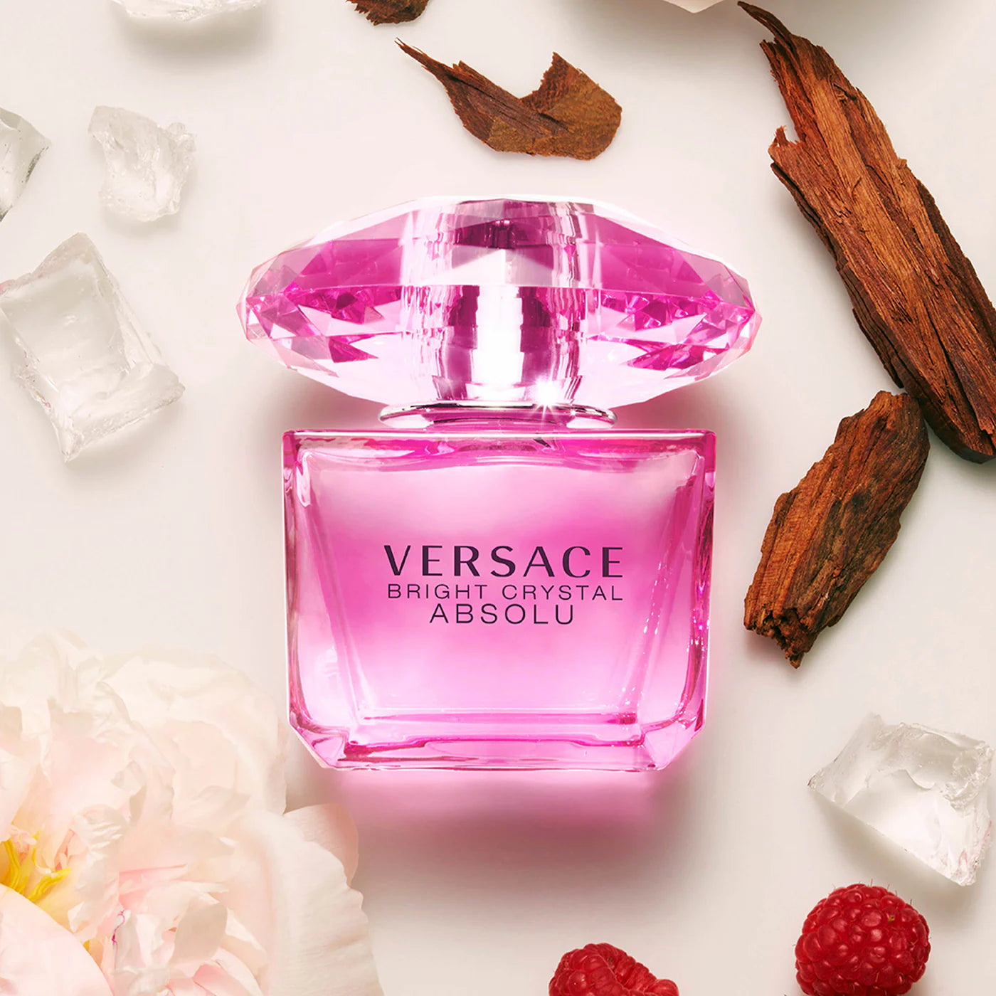 Versace Bright Crystal Absolu perfume bottle with pink diamond cap surrounded by fragrance notes including raspberry, peony, and sandalwood