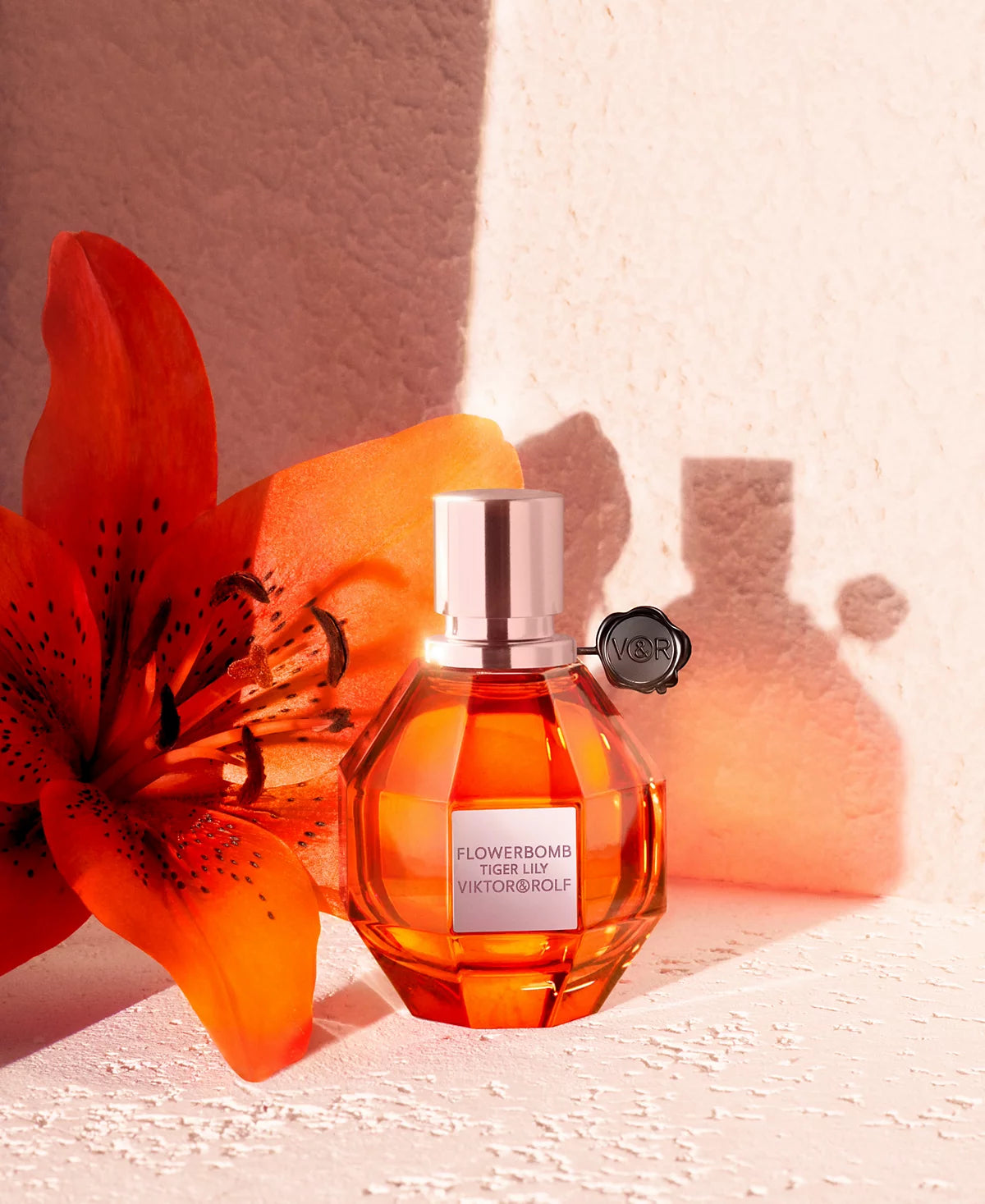Viktor & Rolf Flowerbomb perfume bottle with an orange flower on a textured surface
