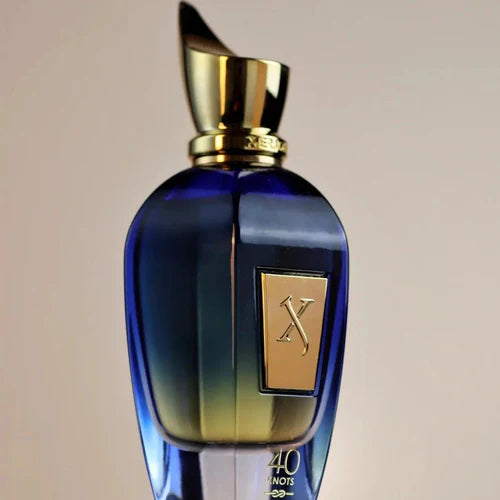 Blue perfume bottle with gold cap and label on a beige background